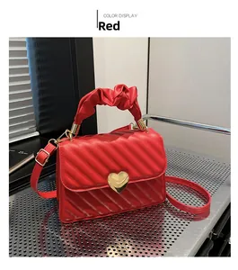 Detail of red quilted PU leather handbag with golden heart clasp and pleated handle
