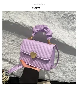 Detailed view of the purple quilted handbag featuring a unique ruched handle and gold heart clasp