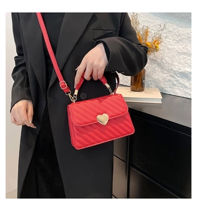 Dettaglio della borsa trapuntata rossa con chiusura a cuore dorata e modella in abito nero