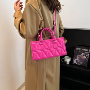 Quilted geometric fuchsia crossbody bag with handle and wide strap on trench coat