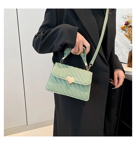 Dettaglio della piccola borsa quadrata trapuntata verde chiaro con chiusura a cuore