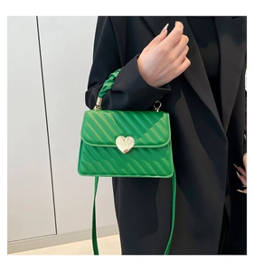 Primer plano del bolso mini acolchado verde brillante con un cierre de corazón de metal dorado