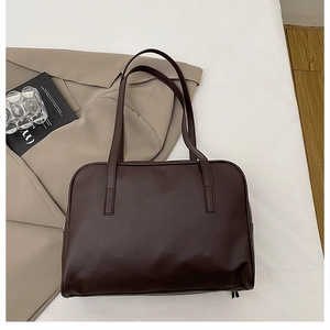 Flat lay of large coffee brown tote bag on beige blazer with minimalist props