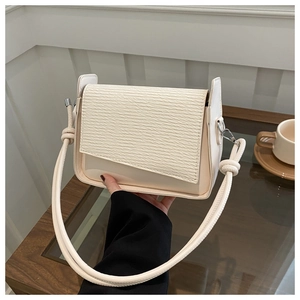 Dettaglio della borsa a tracolla crema con texture a contrasto e design del manico annodato