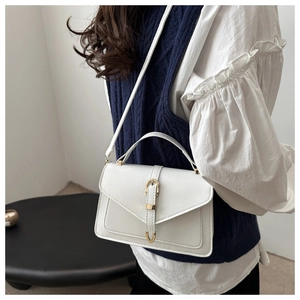 White leather envelope crossbody bag with gold buckle accessory shown on a model