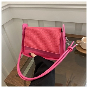 Dettaglio borsa a tracolla rosso rosa con patta strutturata e design asimmetrico