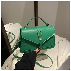 Close-up of green envelope crossbody bag with gold metal buckle and top handle detail