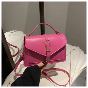 Detail of rose red leather crossbody bag with golden horseshoe buckle and top handle
