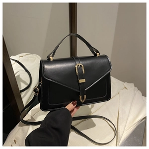 Detail of a vintage black leather handbag with a golden horseshoe buckle and top handle