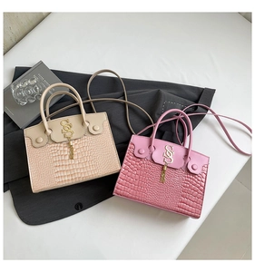 Détail de sacs à main à motif crocodile avec logo S en métal et pompons élégants