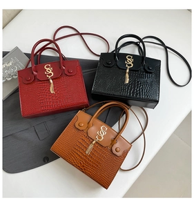 Trois sacs à main élégants en crocodile rouge, noir et marron avec pompons métalliques