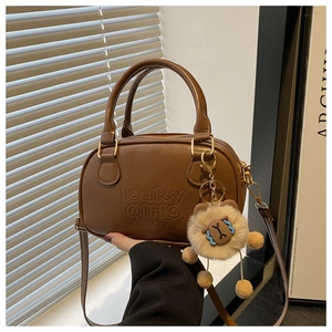 Detail of vintage brown Boston bag with embossed text and plush lion charm accessory