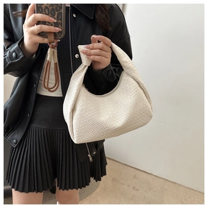 Detail of white woven hobo bag with a signature knotted handle held by a model
