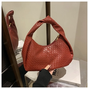 Dettaglio della borsa hobo intrecciata rosso mattone con manico annodato e zip dorata