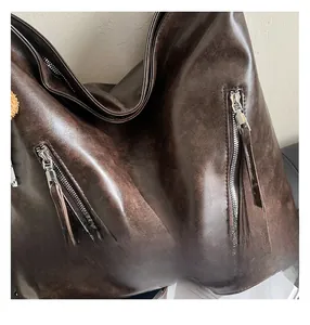Close-up of dark brown vintage faux leather tote with textured surface and dual zipper pockets
