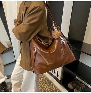 Detail of vintage brown leather hobo bag with zip accents and plush bear charm