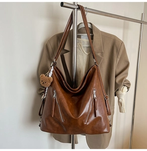 Detail view of retro brown faux leather tote bag with vertical zippers and bear charm