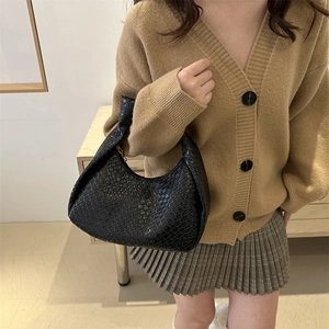 Borsa hobo nera intrecciata con nodi decorativi mostrata in un contesto lifestyle