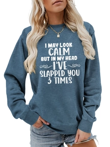 Detail view of blue long sleeve sweatshirt with white slogan and gold pendant necklace