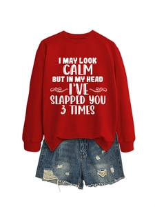 Flat lay of a red sweatshirt with 'I May Look Calm' quote paired with denim shorts