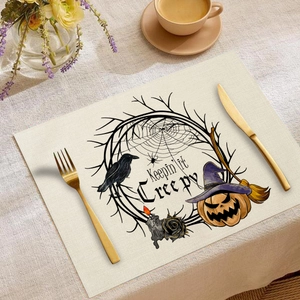 Detailaufnahme eines Leinentischsets mit Halloween-Kürbis, Krähe und gruseligen Motiven