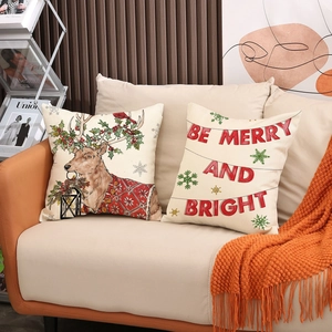 Set of 2 Christmas reindeer and Be Merry printed pillow covers on a cozy sofa