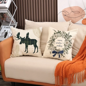 Set of two Christmas elk and wreath linen pillow covers on a cozy sofa setting
