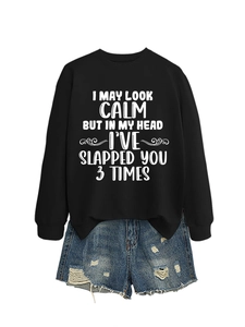 Flat lay of black sweatshirt with humorous quote and distressed denim shorts set