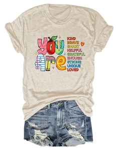 Detail of cream t-shirt with colorful inspirational text and distressed denim shorts