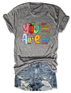 Detail view of casual gray t-shirt with inspirational text and ripped denim shorts