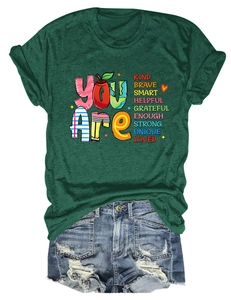 Detail of dark green crew neck tee with colorful You Are Kind Brave slogan and denim shorts