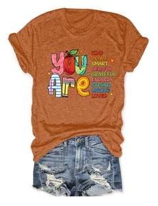 Flat lay of burnt orange crew neck T-shirt with inspirational graphic and denim shorts