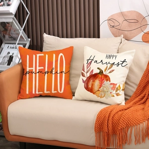 Pumpkin and maple leaf autumn decorative pillow covers on cozy sofa in a home setting
