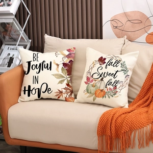 Zweiteiliges Set herbstlicher Kissenbezüge aus Leinen mit Kürbis-Motiv auf dem Sofa