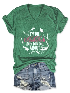 Detailed flat lay of green V-neck T-shirt with nail tech graphic and ripped denim shorts