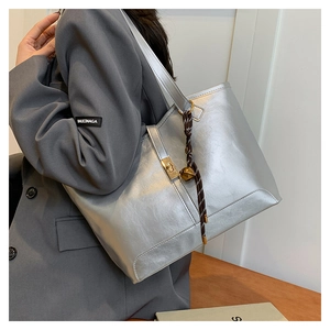 Détail du sac fourre-tout argenté avec fermoir doré et pendentif en corde tressée