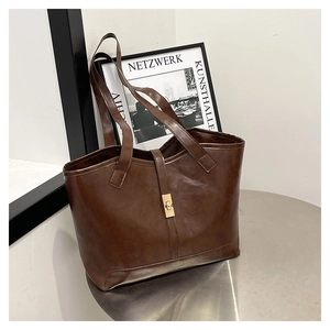 Détail d'un sac cabas marron foncé avec texture cuir et boucle en métal doré chic