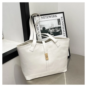 Détail d'un sac cabas en cuir beige avec un fermoir tournant rectangulaire doré vintage
