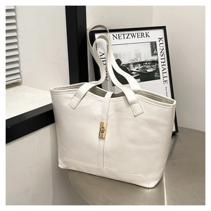 Détail du sac cabas en cuir crème avec fermoir tournant doré et longue bandoulière