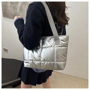 Detail of silver quilted puffer tote bag showing metallic texture and wide strap