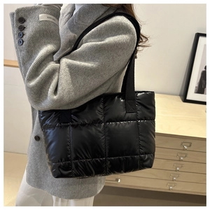 Close-up of black quilted down tote bag showing glossy texture and puffer stitching