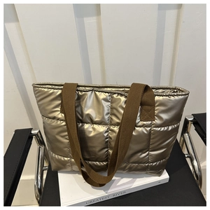 Detail of metallic gold quilted tote bag with brown straps on a book stand