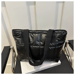 Detail of a black quilted puffer tote bag on a modern chair for a minimalist fashion look