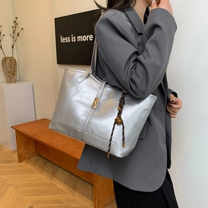 Sac fourre-tout argenté métallisé avec fermoir doré porté par un mannequin en costume