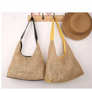 Detail of handwoven straw tote bags with contrast PU leather handles in a wall display