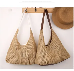 Detail of woven straw tote bags with white and brown leather straps on a wooden hanger