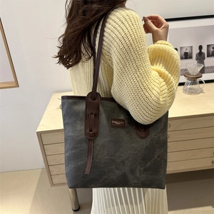 Vintage grey canvas tote bag with brown leather handles in a cozy home setting