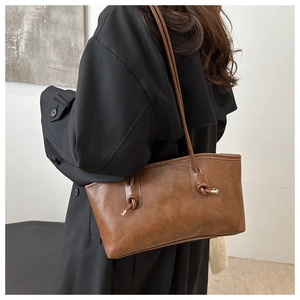 Detail of vintage brown tote bag with knot shoulder strap and gold-tone hardware