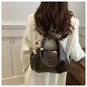 Detail of dark brown leather backpack for women with a cute lion plush keychain