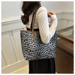 Detail of leopard print tote bag with brown leather straps and gold rivet accents